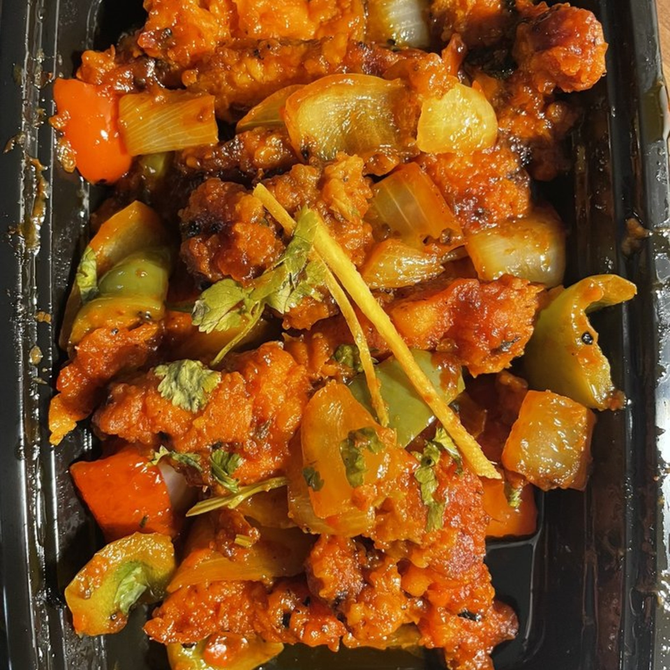 Close-up of Bay Leaf Indian Kitchen's chili chicken with bell peppers, onions, and cilantro.